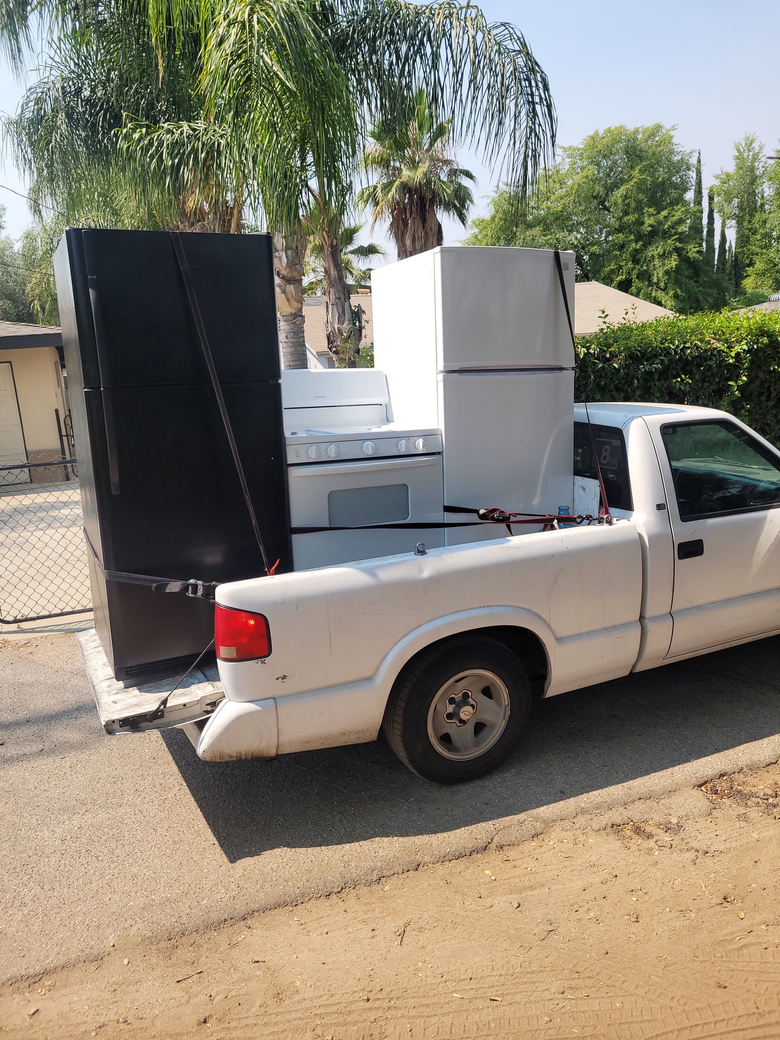Pickup truck carrying several used household appliances including refrigerators and an electric range, from our appliance photo collection